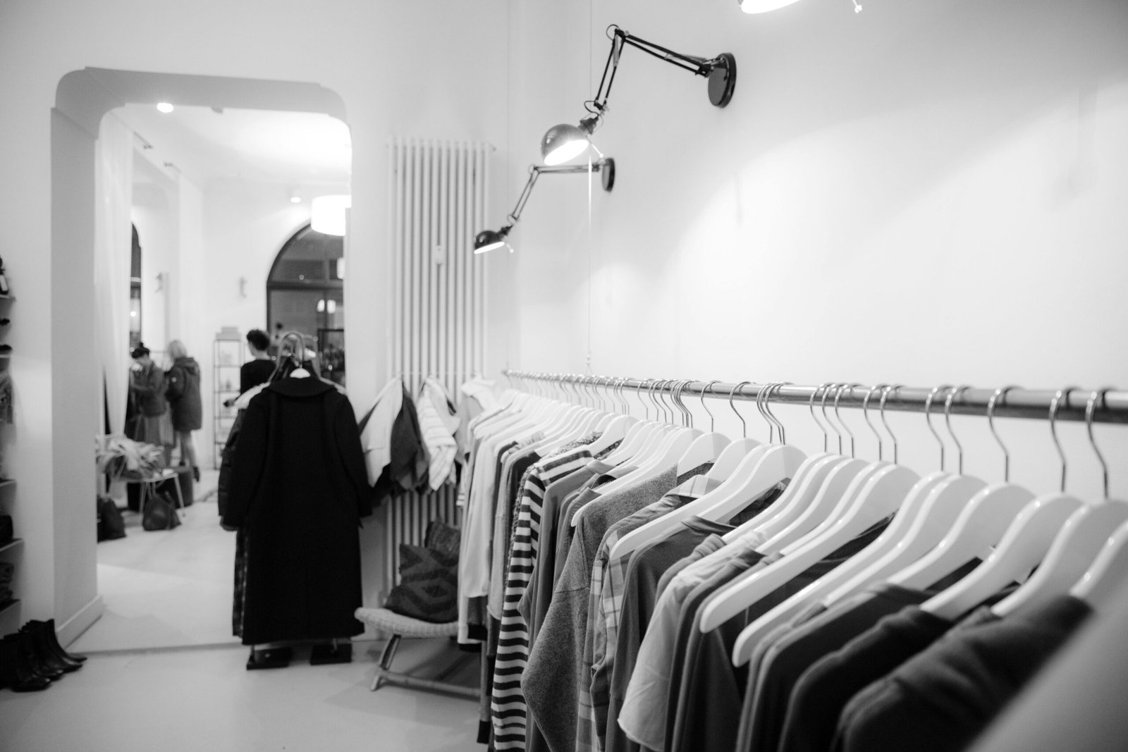 Stylish black and white interior of a boutique with clothes on racks, showcasing modern fashion.